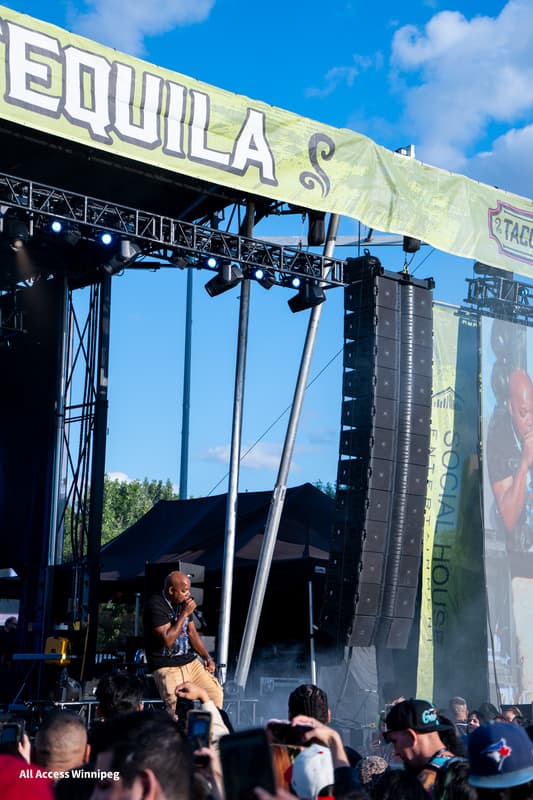 Performer on the main stage under the Tacos & Tequila banner, crowd holding up phones